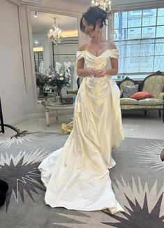 a woman in a white wedding dress looking at her cell phone while standing on the floor