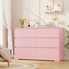 a pink dresser sitting in a living room next to a window