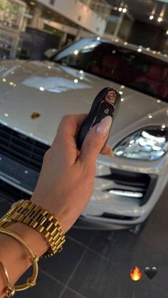 a hand holding a remote control in front of a car