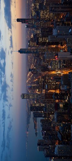 the city skyline is lit up at night with clouds and blue sky in the background