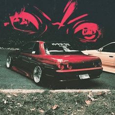 two cars parked next to each other in front of a wall with graffiti on it