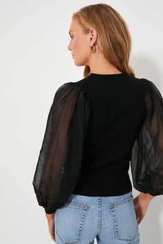 Not your average going out top — the Black Betsy Knit Blouse is the cool-girl closet update you've been needing. Featuring a classic high round neckline and a slim fitting bodice, complimented by fabulous, statement-making sheer balloon sleeves to add a hint of extra dimension. Perfect for pairing with mini skirts, denim, trousers and more for any evening plans on your social calendar, you're sure to get plenty of mileage out of this cool silhouette. Crewneck Long sheer balloon sleeves Fitted bo Fitted Mesh Top With Crew Neck For Evening, Elegant Pointelle Knit Tops For Night Out, Black Top With Sheer Puff Sleeves, Elegant Pointelle Knit Top For Party, Chic Fine Knit Party Top, Chic Party Fine Knit Tops, Chic Fitted Blouse With Crew Neck, Fall Mesh Top With Sheer Sleeves And Crew Neck, Spring Pointelle Knit Tops For Night Out