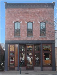 an old brick building with three windows on the front and two doors to the second floor