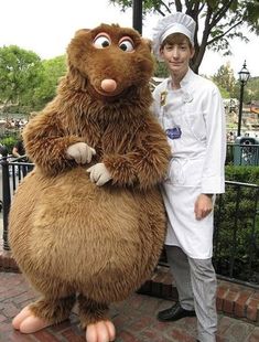 a man in a chef's outfit standing next to a giant stuffed animal character