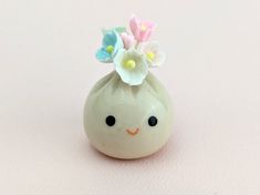 a small ceramic vase with flowers in it's head on a pink surface,