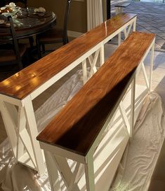 a wooden bench sitting on top of a hard wood floor next to a dining room table