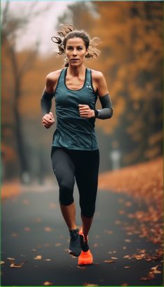 a woman running down a road in the fall with leaves on the ground and trees behind her