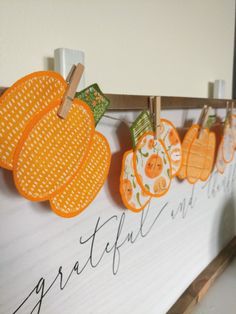 an orange and white sign with pumpkins hanging from it's clothes pins on the clothes line