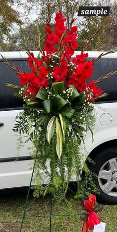 a white van parked next to a bouquet of red flowers on top of a grass covered field