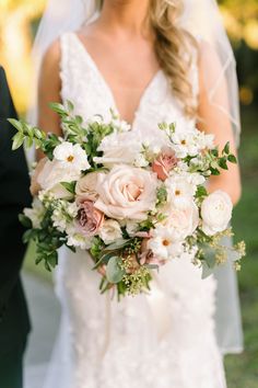 a bride holding a bouquet of white and pink flowers