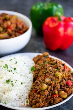 a white plate topped with rice next to two bowls filled with chili and green beans