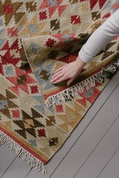 a person is reaching for a rug on the floor