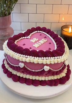 a heart shaped cake on a plate with candles in the background