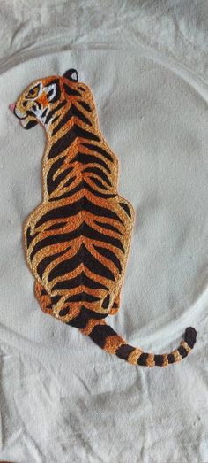 an embroidered tiger sitting on top of a white cloth