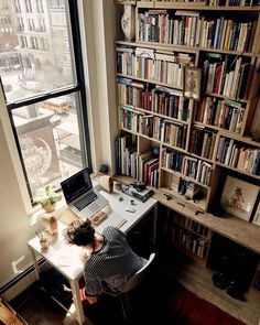 a person sitting at a desk in front of a book shelf with books on it