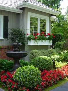 a house with flowers in the front yard and a birdbath on the side