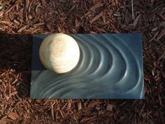 a white ball sitting on top of a black mat in the ground next to wood chips