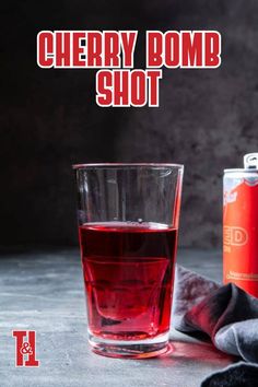 a red drink in a glass next to a can of cherry bomb shot