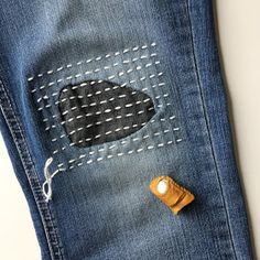 a pair of blue jeans with an embroidered patch on the side and a wooden button in the pocket