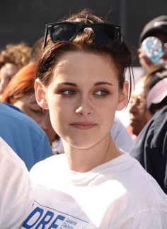 a woman with sunglasses on her head posing for the camera in front of a crowd