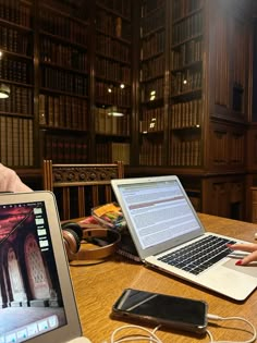 two laptops sitting on a table in front of bookshelves