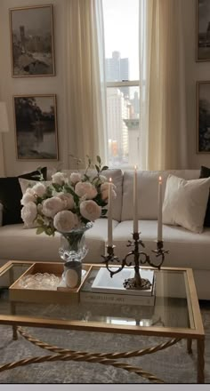 a living room filled with furniture and flowers on top of a coffee table in front of a window