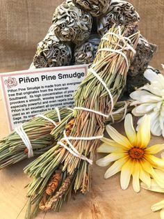 some dried flowers sitting on top of a wooden table next to a sign that says pinon pine smudge