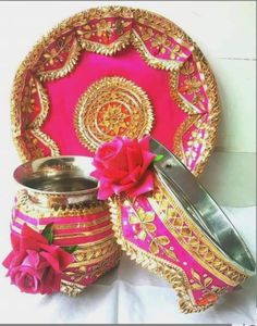 a pink and gold plate with some red flowers on the side, sitting next to it