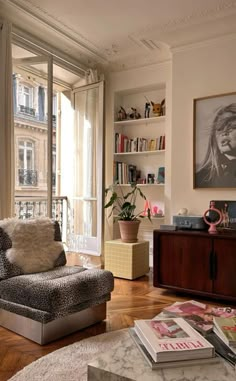 a living room filled with lots of furniture and books on top of a hard wood floor