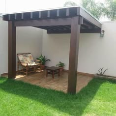 an outdoor patio area with wooden furniture and green grass on the ground, next to a white wall