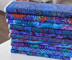 a stack of colorful fabrics sitting on top of a white table next to each other