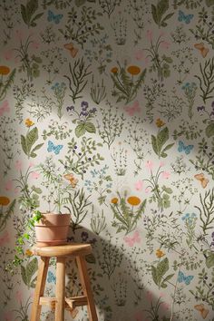 a small stool sitting in front of a wall with flowers and plants painted on it