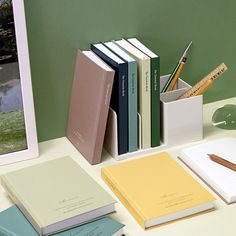 three books are stacked on top of each other next to a pen and pencil holder