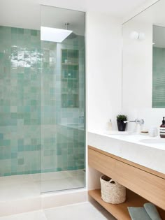 a bathroom with a glass shower door next to a white sink and wooden counter top