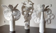 three vases made out of toilet paper with flowers and leaves on the top one