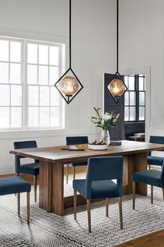 a dining room table with blue chairs and a potted plant