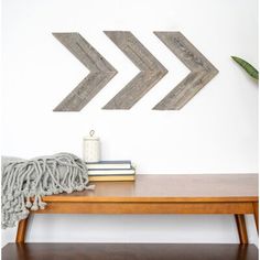 two wooden arrows are hanging on the wall above a table with books and a blanket