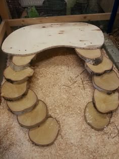 a bench made out of wood slices on top of some sand in a caged area