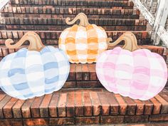 three painted pumpkins sitting on top of brick steps