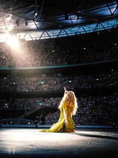 a woman sitting on the ground in front of a crowd at a concert or show