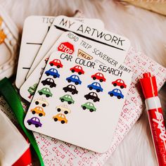 some cards with cars on them are next to cookies and a christmas tree in the background