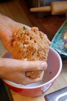 a person holding something in their hand while sitting at a table with other food items