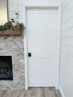 a white door in front of a brick fireplace