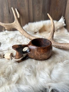 a wooden bowl sitting on top of a white fur covered floor next to antlers