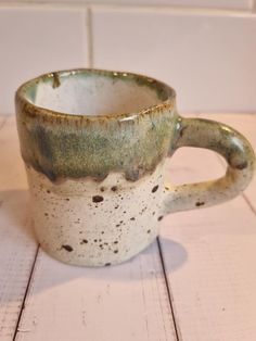 a white and green cup sitting on top of a wooden table