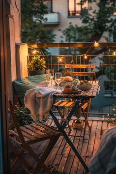 Cozy balcony setting with a wooden table, chairs, dinner setup, draped blanket, and string lights, creating a warm evening atmosphere. Small Balcony Seating, Balcony Seating Ideas, Verandah Decor, Balcony Styling, Emerald Green And Orange, Balcony Renovation, Hanging Seating, Balcony Seating, Bedroom Deck