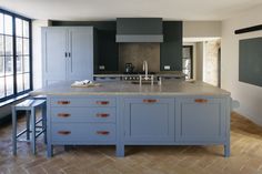 a large kitchen with blue cabinets and marble counter tops in front of a chalkboard