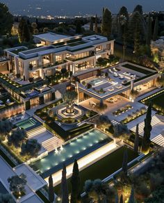 an aerial view of a mansion at night with lights shining on the building and pool area