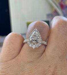 a person's hand with a diamond ring on top of their finger and an engagement band in the middle