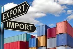 two black and white street signs on top of colorful shipping containers under a blue sky with clouds